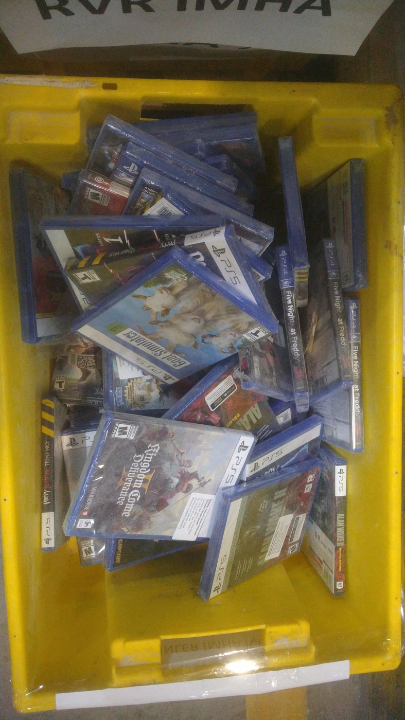 A yellow warehouse tote full of sealed PS5 and PS4 games, including Goat Simulator, Kingdom Come: Deliverance II, Alan Wake 2 and Five Nights at Freddy's
